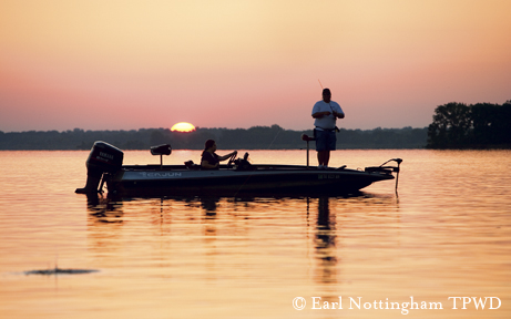bass boat back-lit in the setting sun