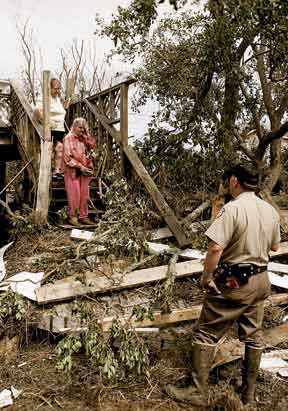 residents look over the debris where their house once was