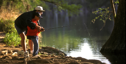 adult helping child fish from bank