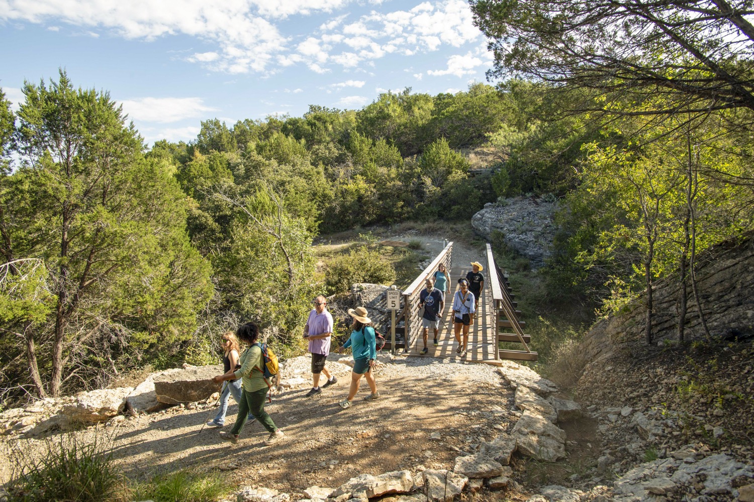 Hikers walk over a footbridge at Palo Pinto Mountains State Park