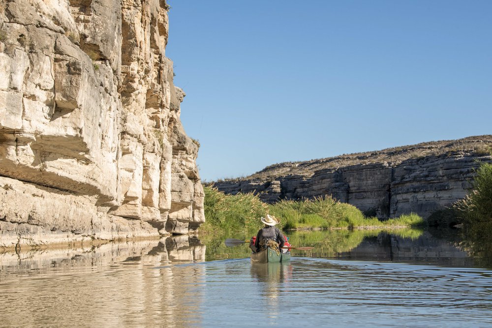 Kayaker paddles along the cliffs of the lower canyon on the Rio Grande River